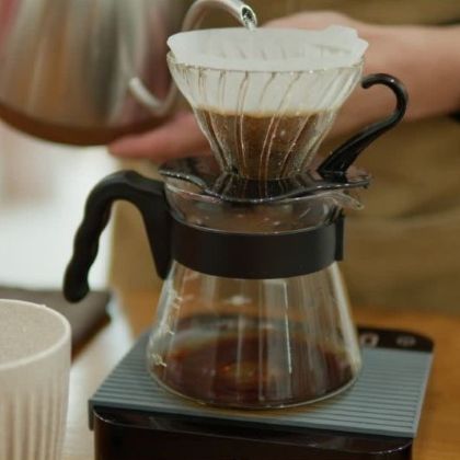 Príprava filtrovanej kávy cez V60 dripper – prelievanie vody cez filter a mletú kávu