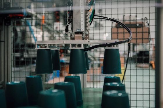 Výroba cestovných hrnčekov na kávu KeepCup – robotická linka s plastovými pohármi v manufaktúre.