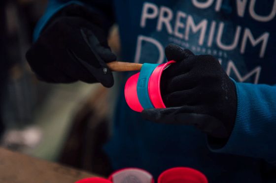 Ručná montáž silikónového pásika na cestovný hrnček na kávu KeepCup počas výroby.